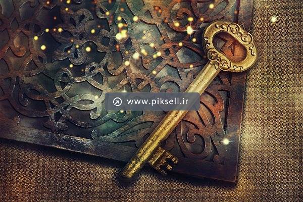 عکس با کیفیت از کلید قدیمی طلایی و کتاب جادویی